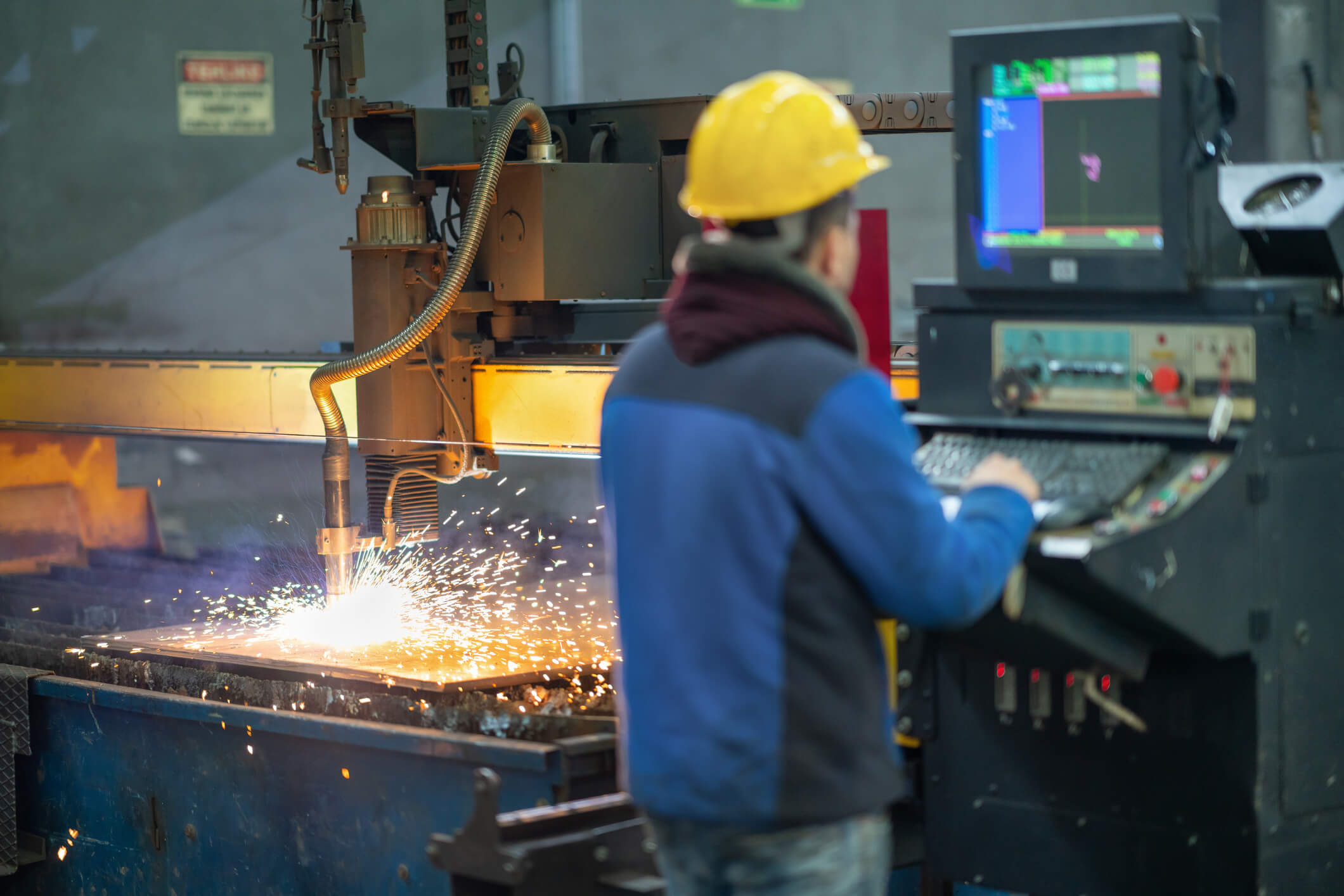 US metal worker operates a plasma cutting machine. 