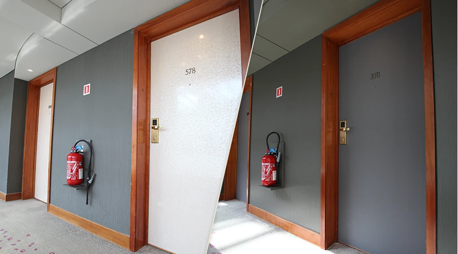 Zdjęcie przedstawia drzwi w przestrzeni użytkowej przed i po renowacji. Po lewej stronie drzwi w jasnym, zużytym wykończeniu z widocznymi śladami eksploatacji. Po prawej stronie efekt po oklejaniu – jednolite, matowe drzwi w nowoczesnym, ciemnoszarym kolorze. Dzięki zastosowaniu folii architektonicznych Cover Styl możliwe było szybkie odświeżenie wyglądu i zwiększenie estetyki przestrzeni. Metamorfoza ilustruje proces oklejania drzwi folią omawiany podczas szkoleń i webinarów z renowacji powierzchni.