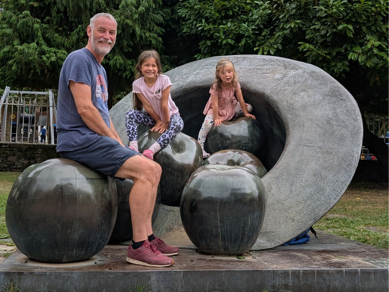 me and my granddaughters on a sculpture of apples and a hat