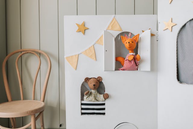 two puppets looking out of windows in a play house