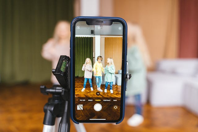 three primary school children filming each other on mobile phones