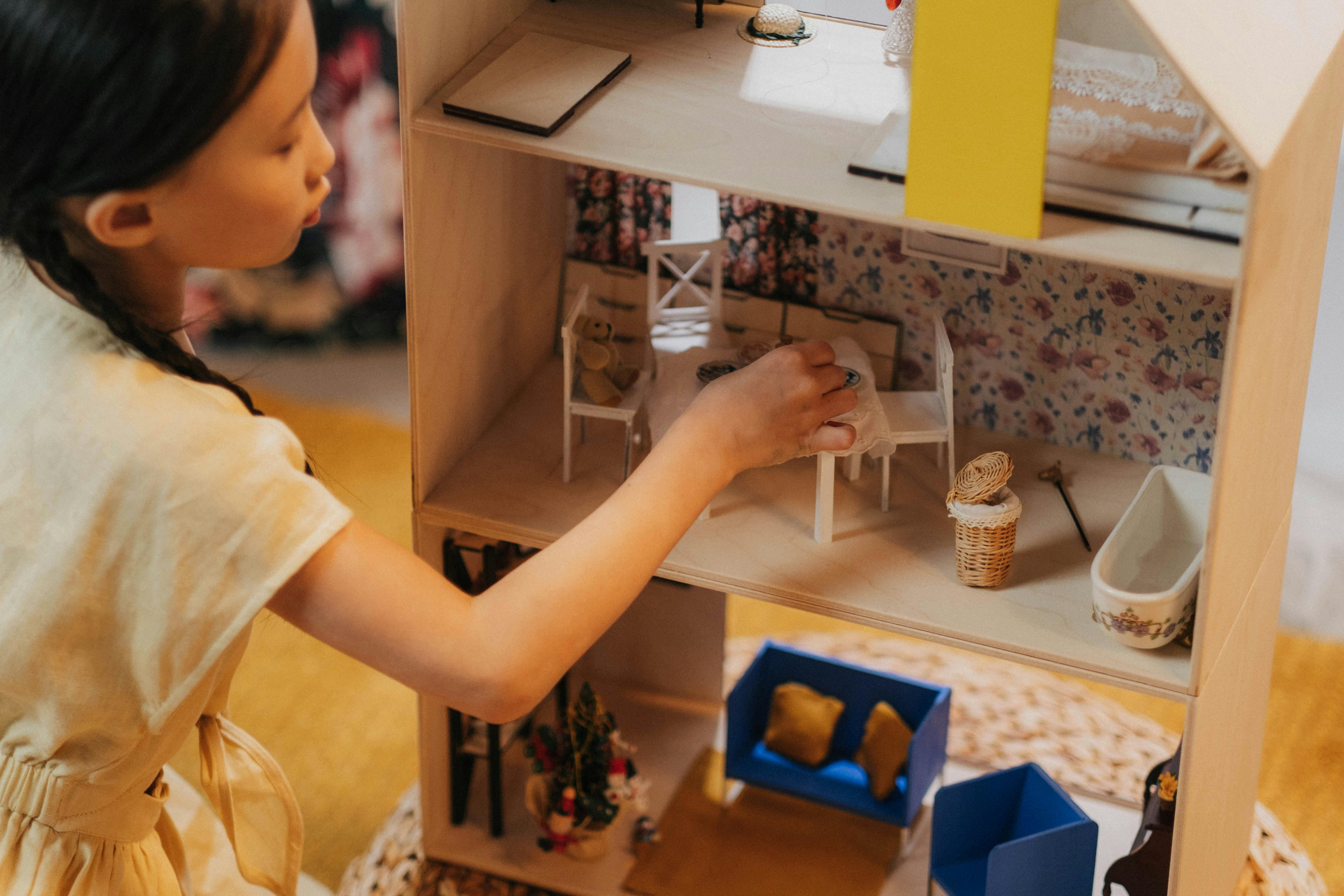 a girl is playing with a mini me in a dolls house