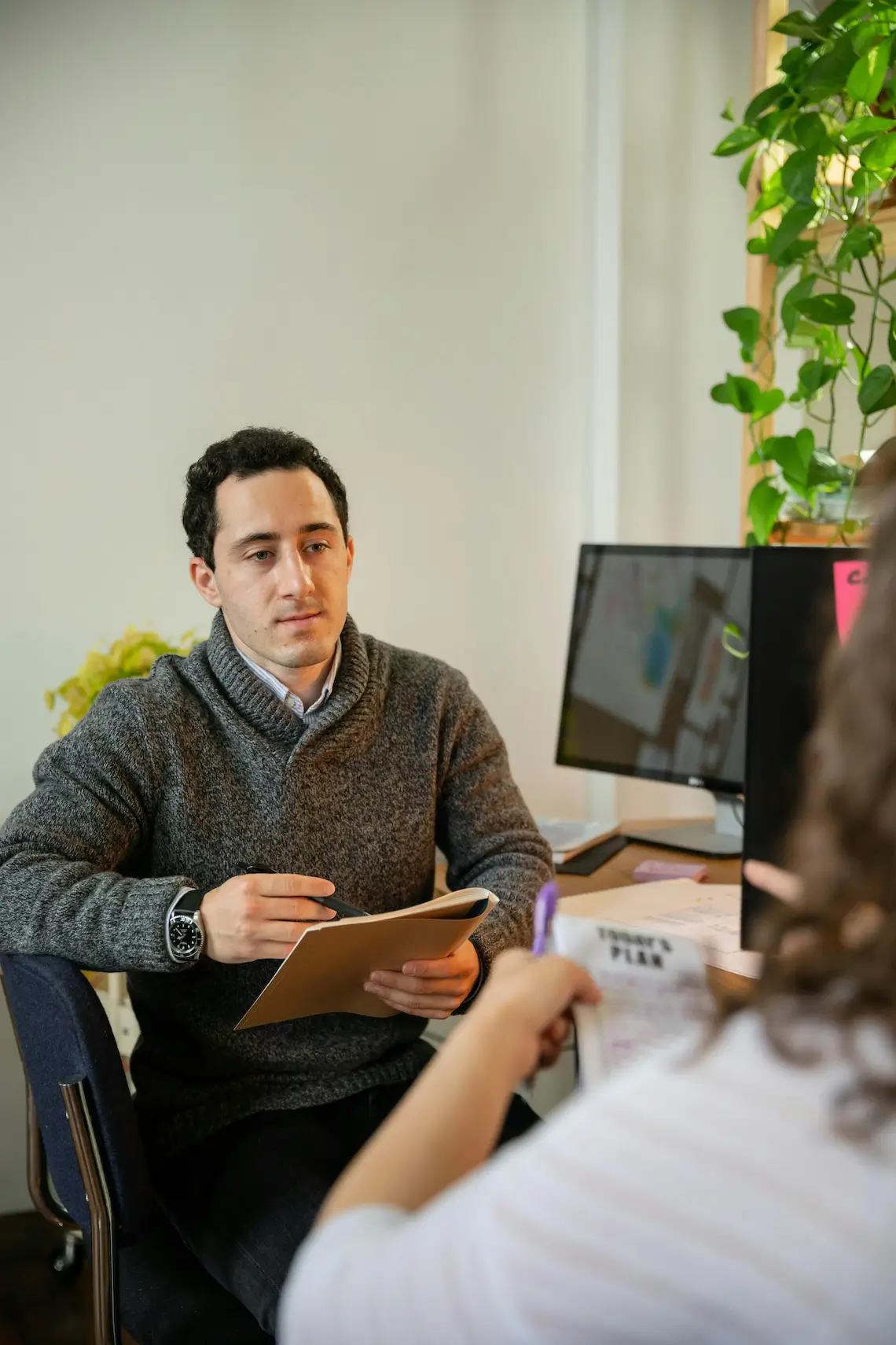 Mann mit Notizbuch sitzt vor Computer