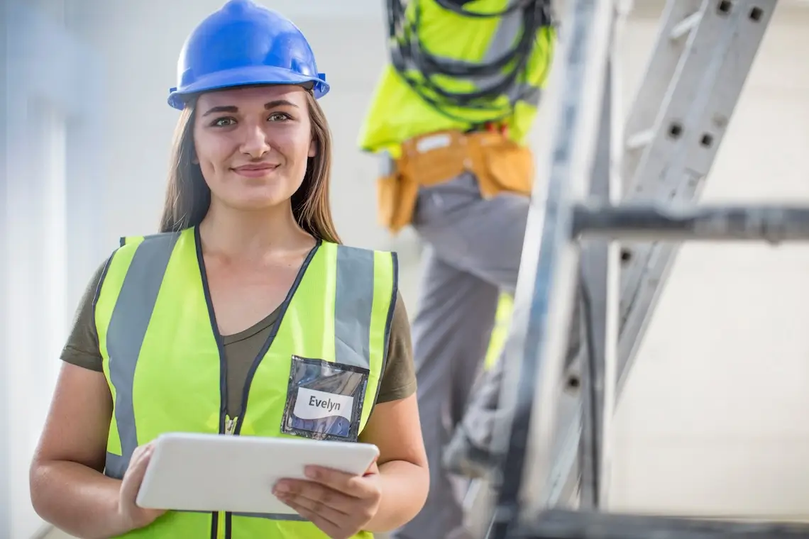 Mensch mit Bauhelm bei der Arbeit mit einem Tablet in der Hand